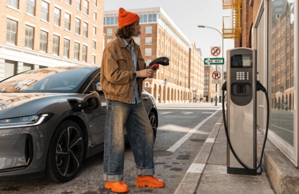 Frustrated EV owner standing at a charging station with mismatched plug and confused expression