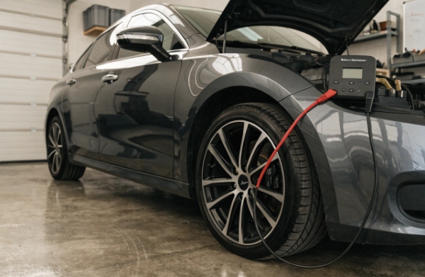 Car parked idle in a garage with a smart battery maintainer connected for long-term storage